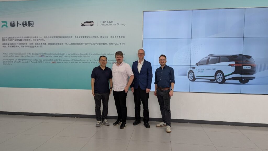 4 personer står ved en hvid væg. SAAM Teamet er på besøg hos Appollo